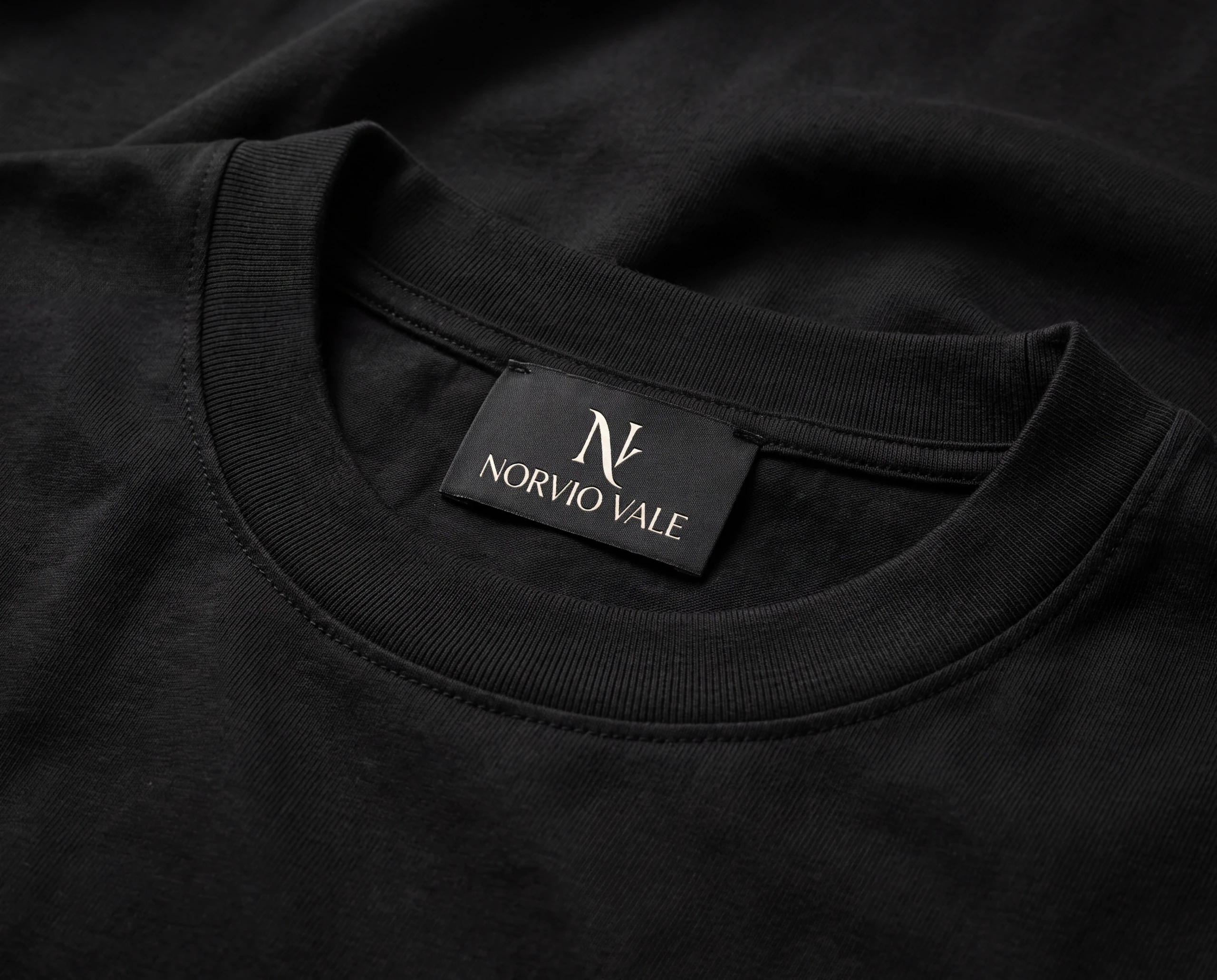 Close-up of the Norvio Vale label, ribbed neckline, and black cotton fabric
